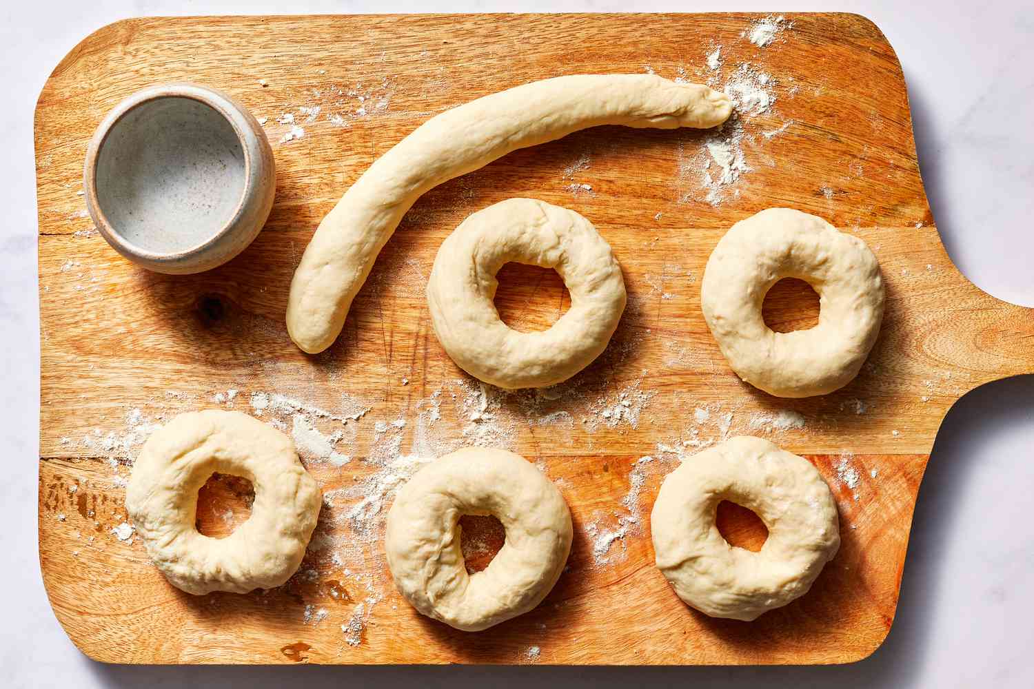 Bagel dough formed into bagels on a floured cutting board 