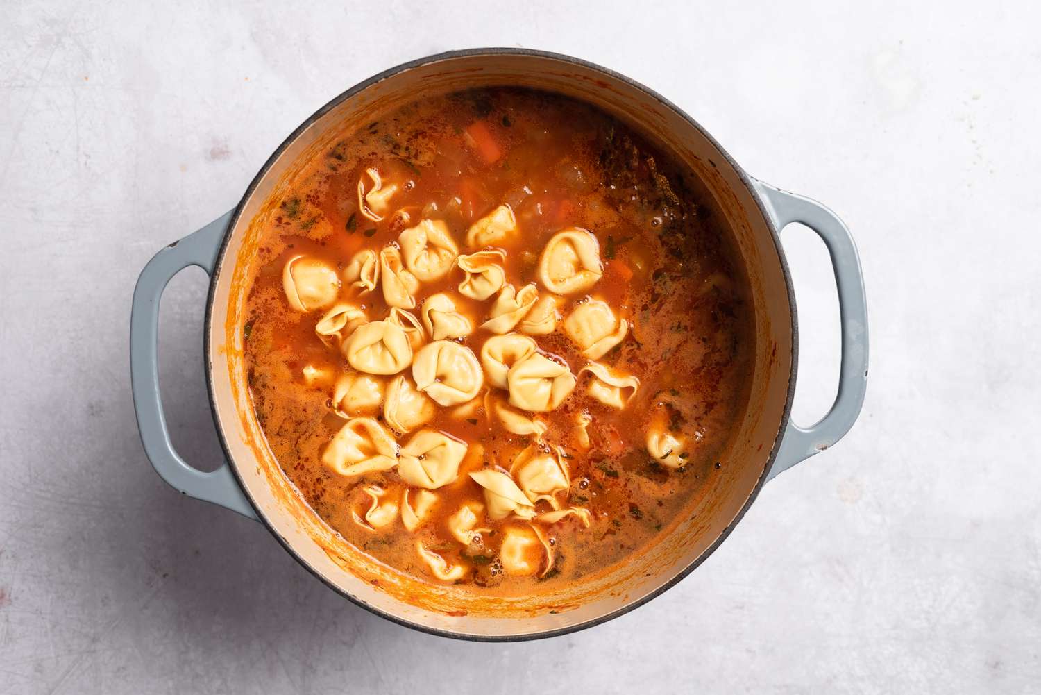 Tortellini added to the pot of vegetable soup