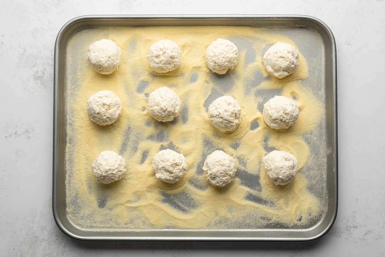 Ricotta balls on top of semolina flour in a rimmed baking sheet