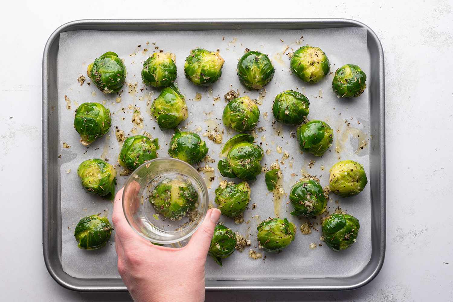 Brussels sprouts smashed with a glass, on a parchment paper lined baking sheet 