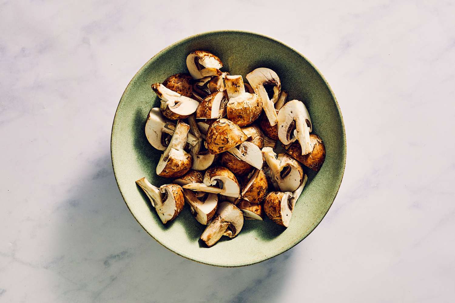 A bowl of cremini mushrooms tossed in oil and seasoned with salt