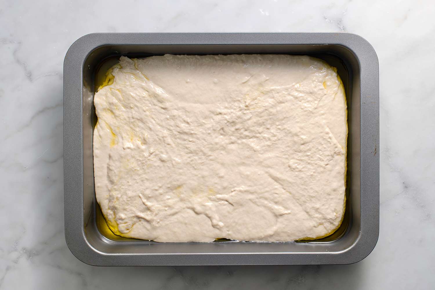 Focaccia dough in a baking pan with oil 