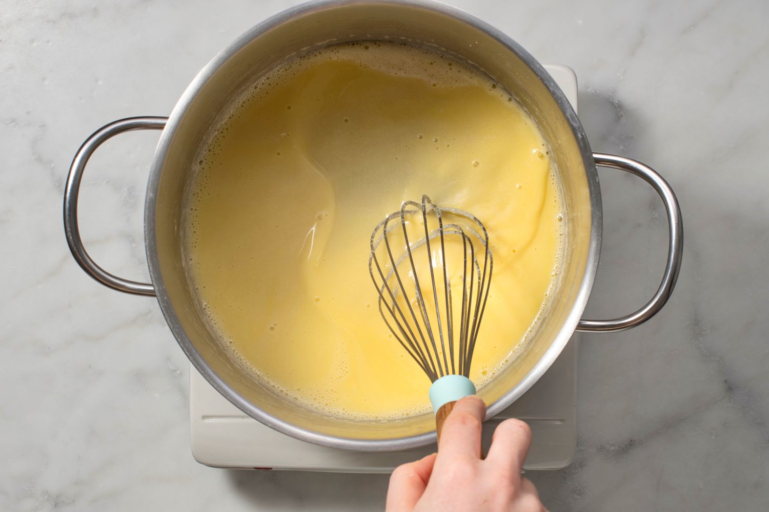 A hand whisking cheese into the butter mixture