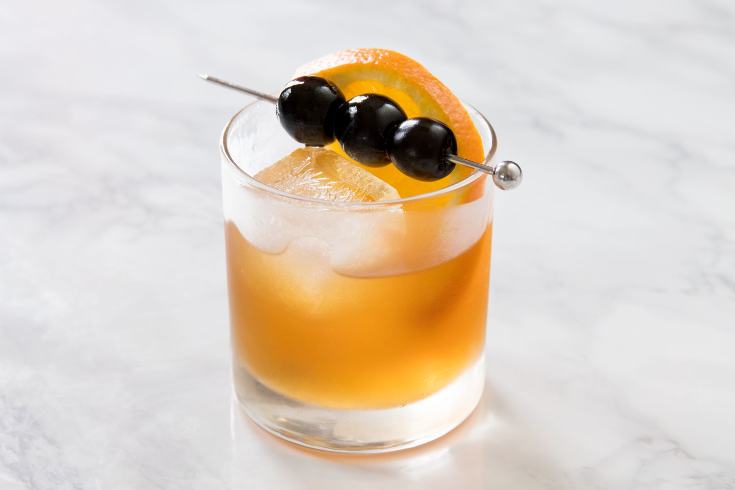 Amaretto sour garnished with an orange slice and real maraschino cherries