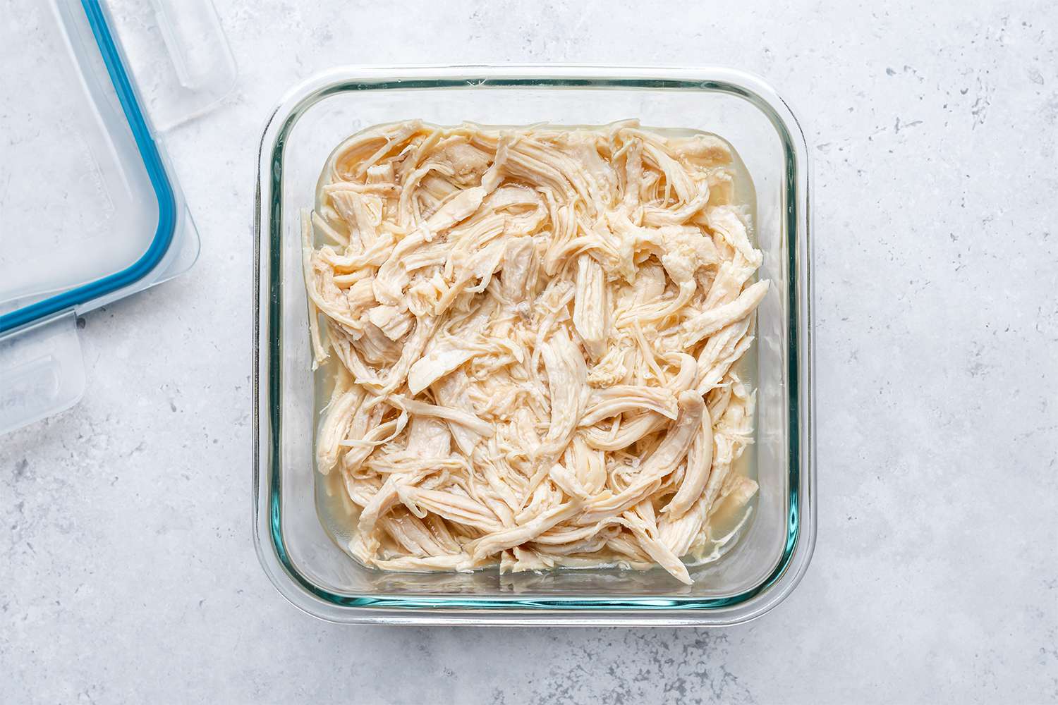 Shredded chicken in broth in a glass container
