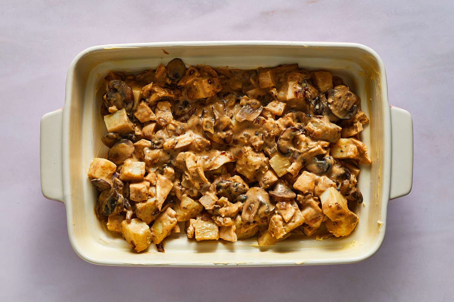 A baking dish with potatoes, chicken, and creamy mushrooms