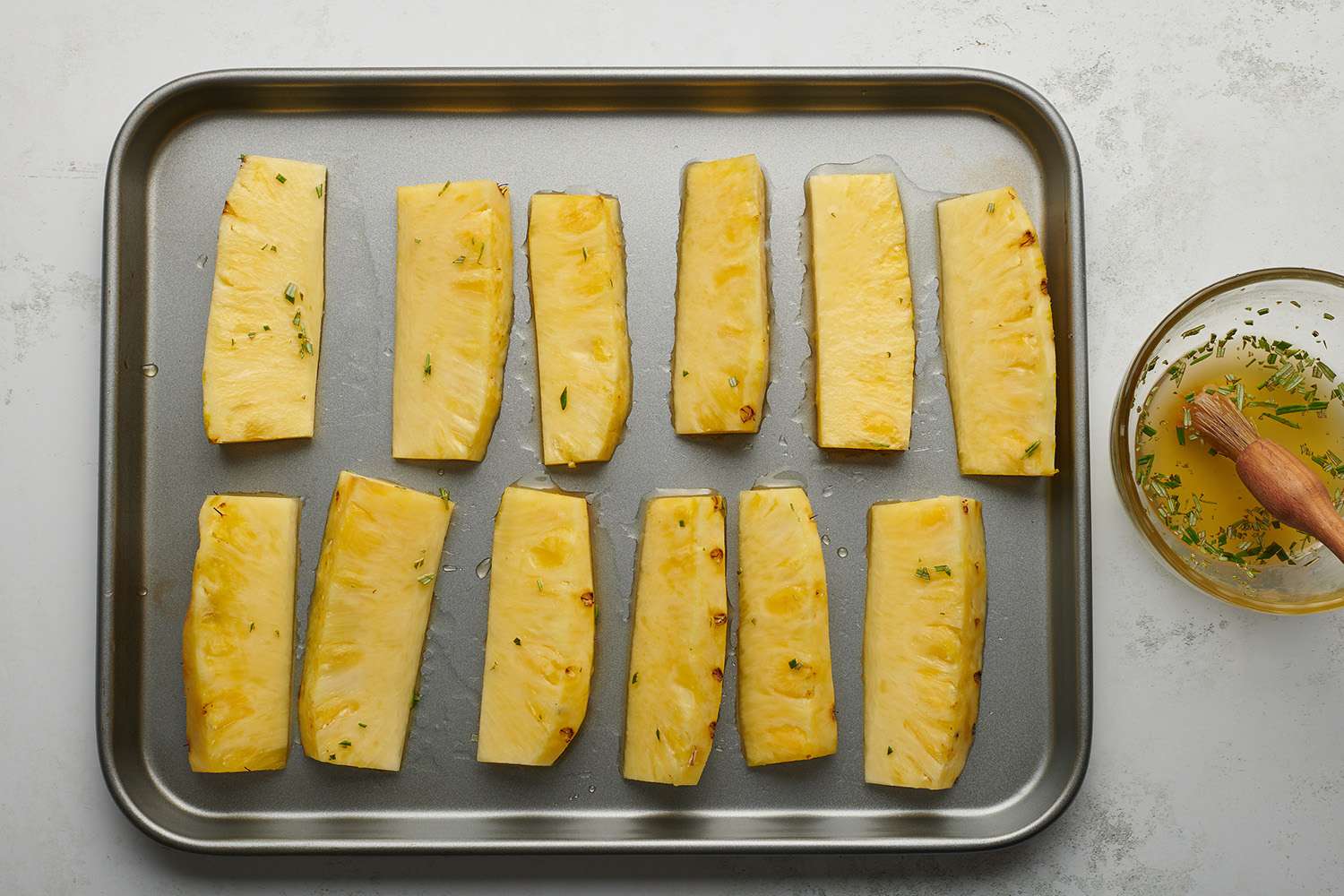 Pineapple slices on a baking sheet, brushed with the honey glaze 