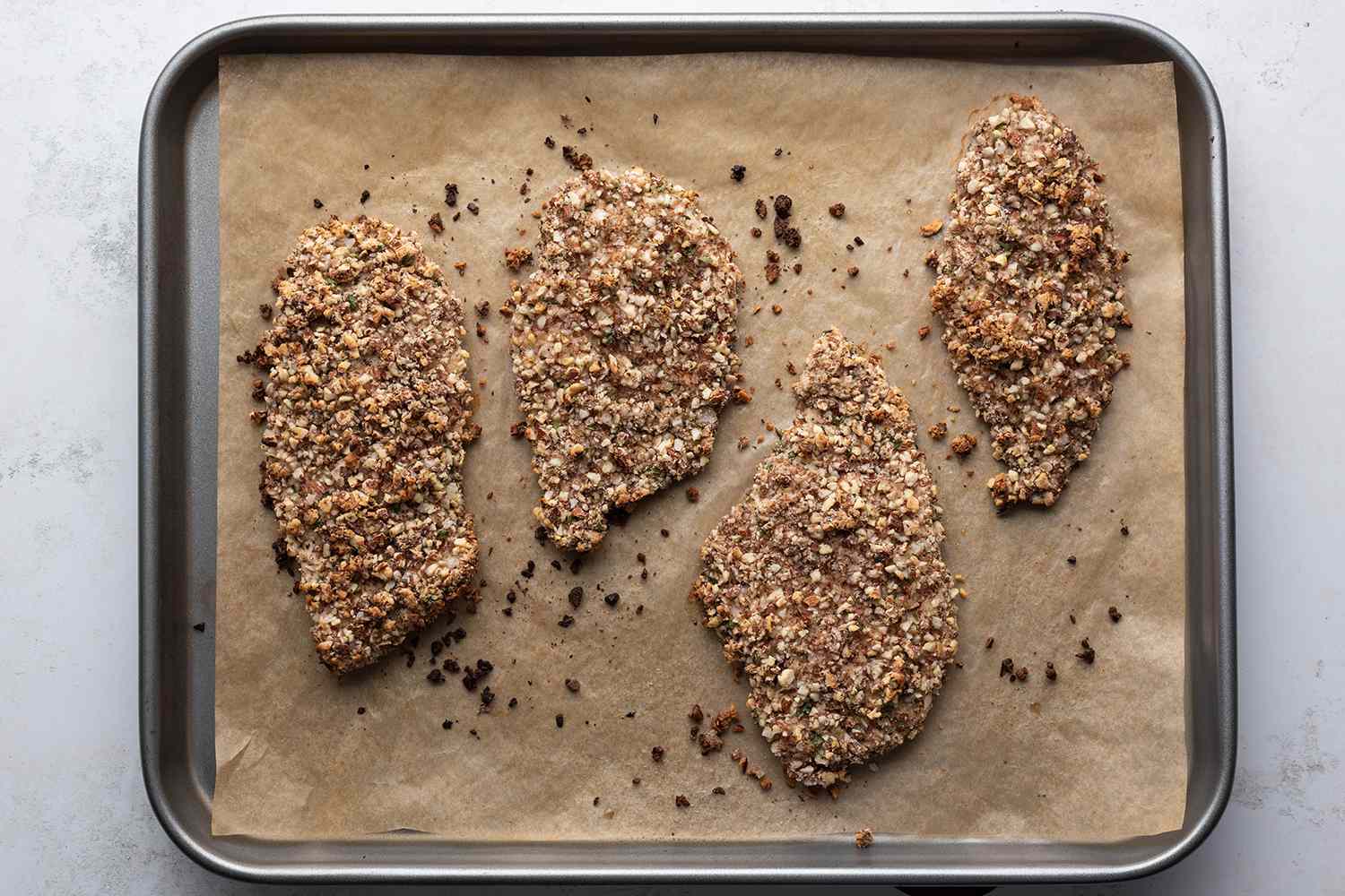 Baked almond crusted chicken on a parchment paper lined baking sheet 