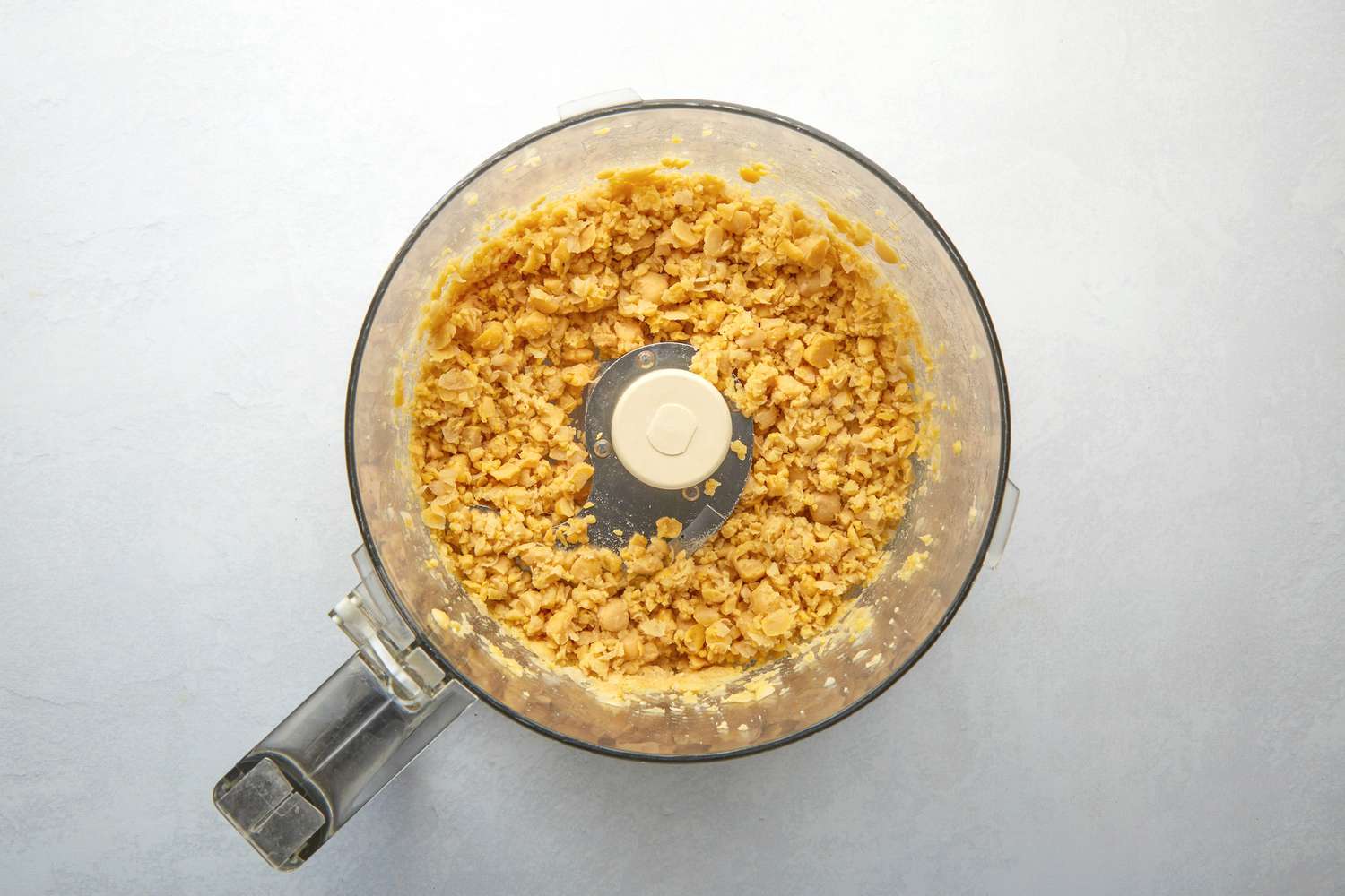 A food processor with crumbled up chickpeas