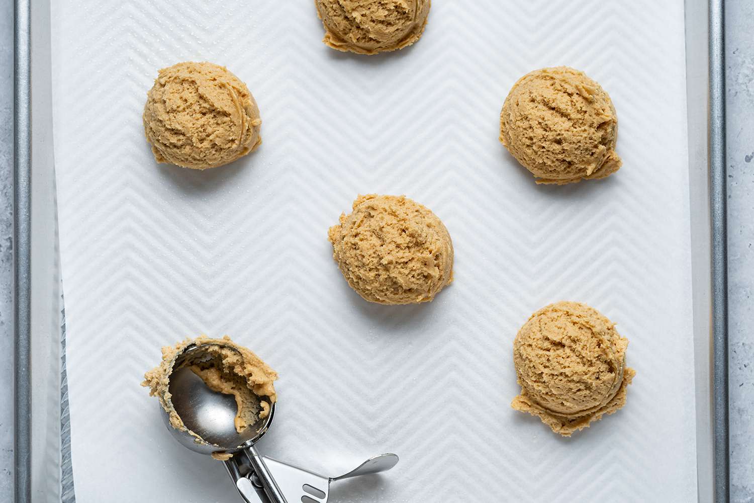 Cookie dough scooped onto a lined baking sheet 