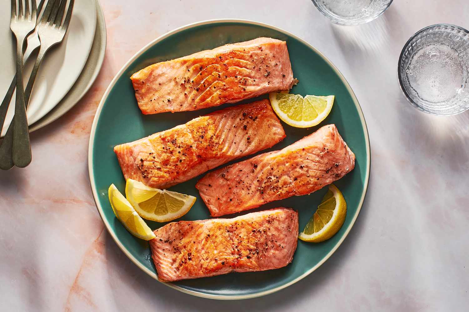 A plate of pan-seared salmon served with lemon slices