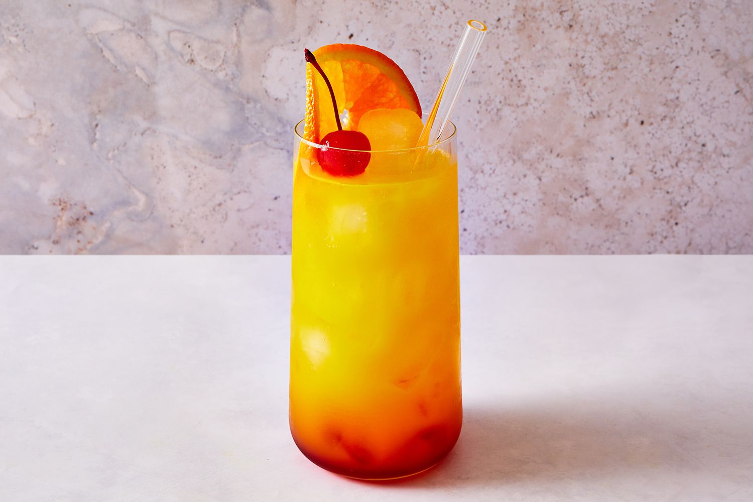 Tequila sunrise cocktail garnished with an orange slice and a cherry