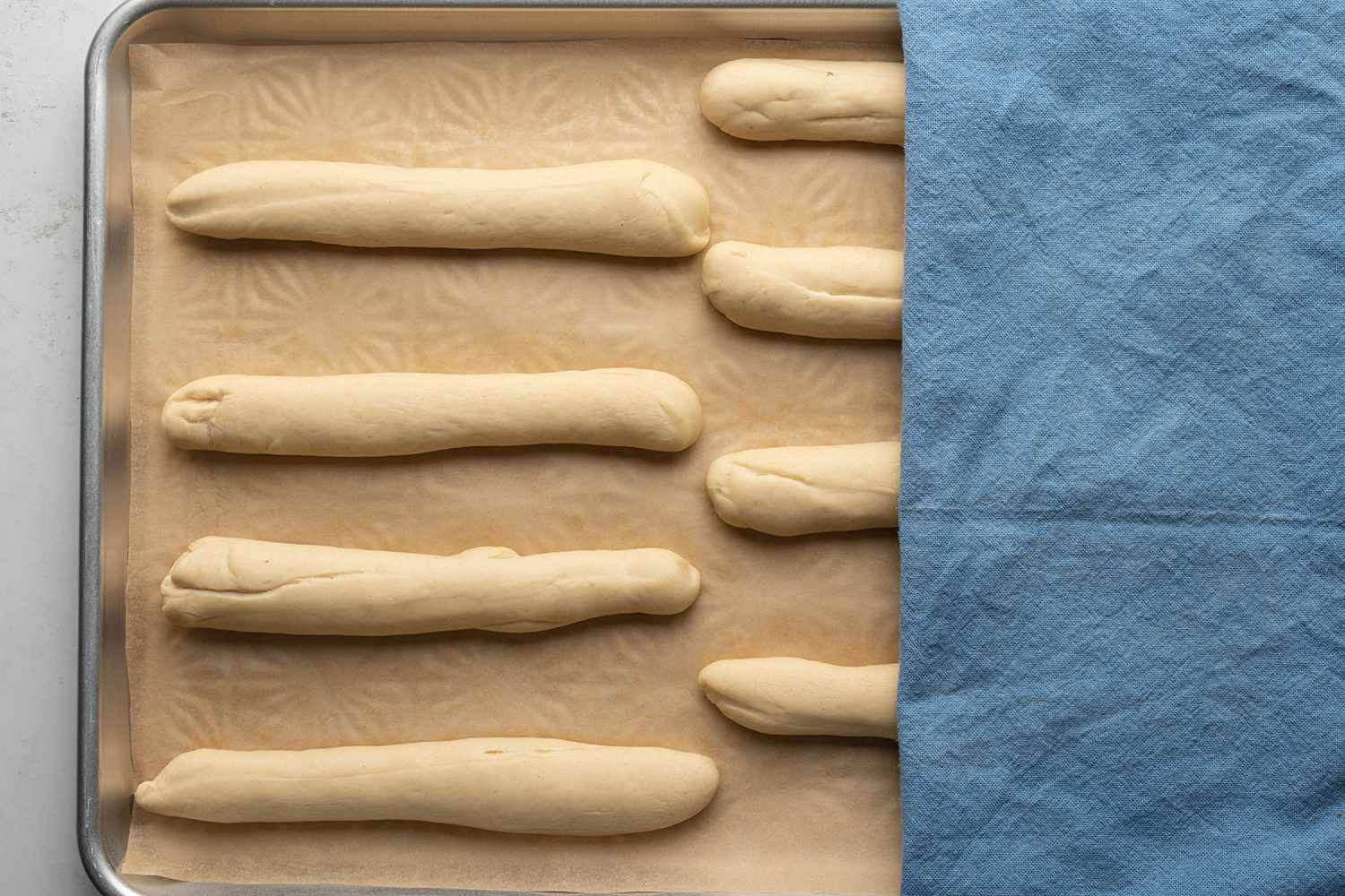 Dough on a lined baking sheet, covered with a towel 