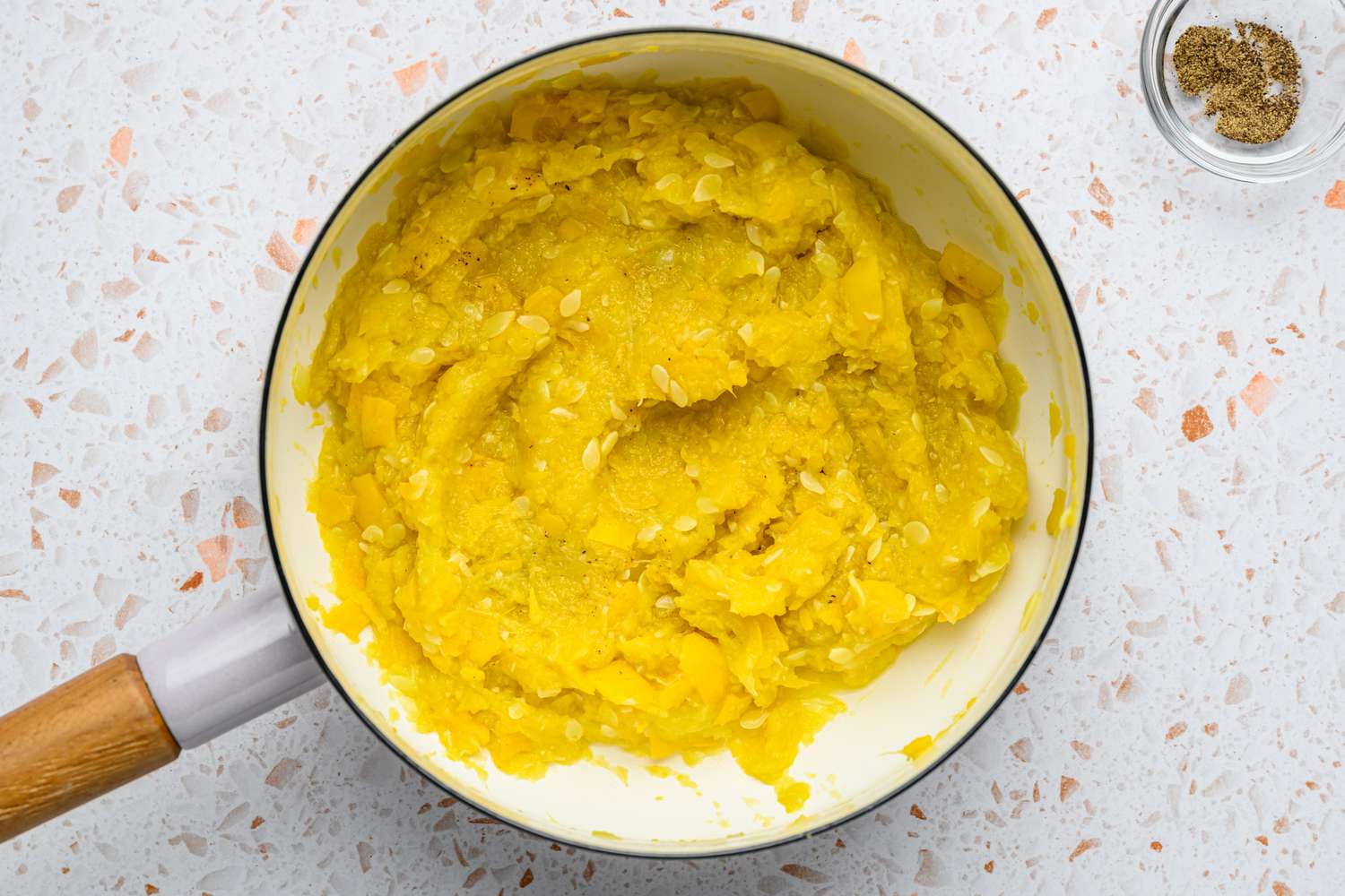 A pan of mashed, cooked squash topped with salt and pepper