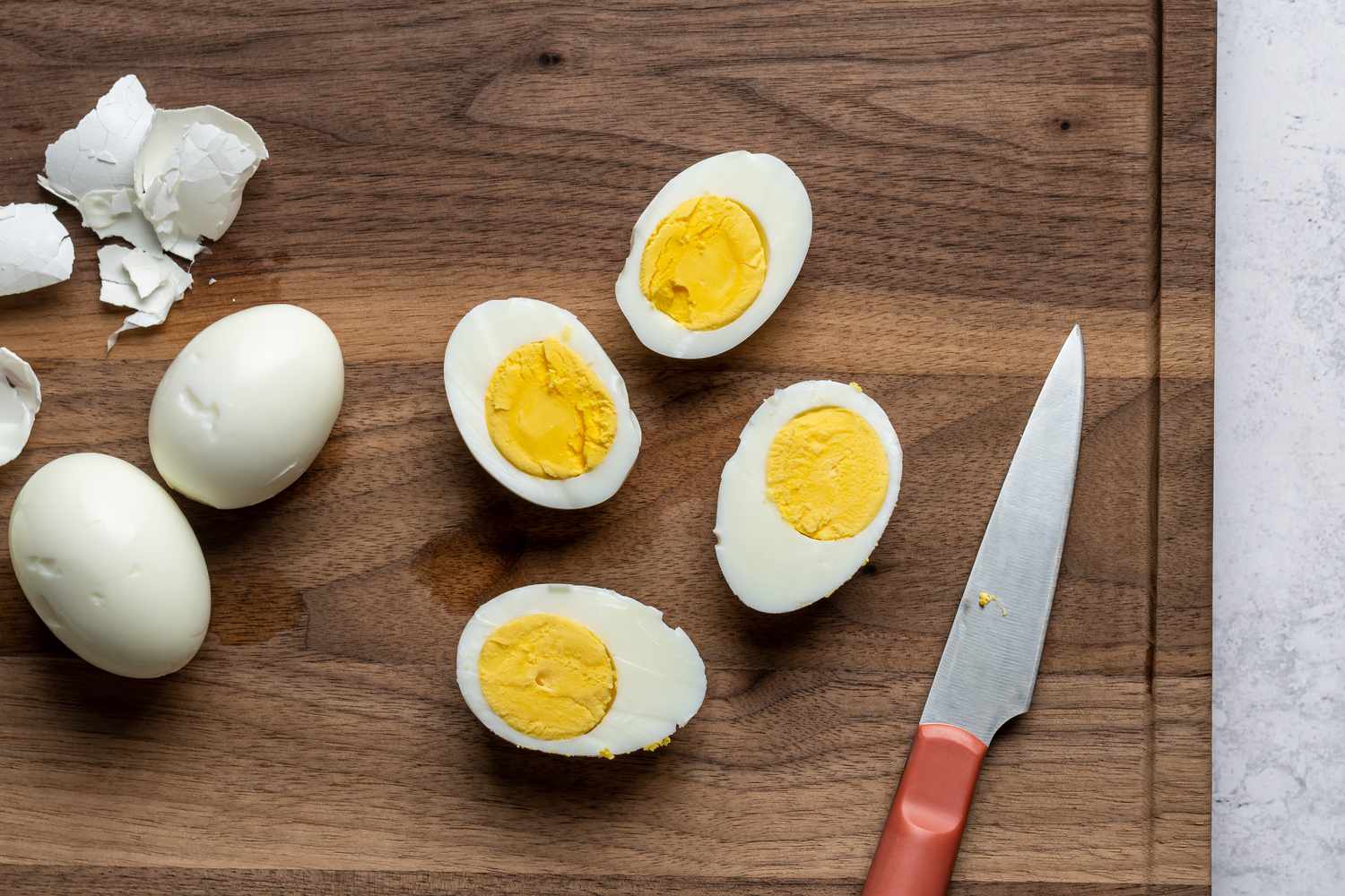 Peeled and sliced hard boiled eggs on a cutting board, next to a knife 