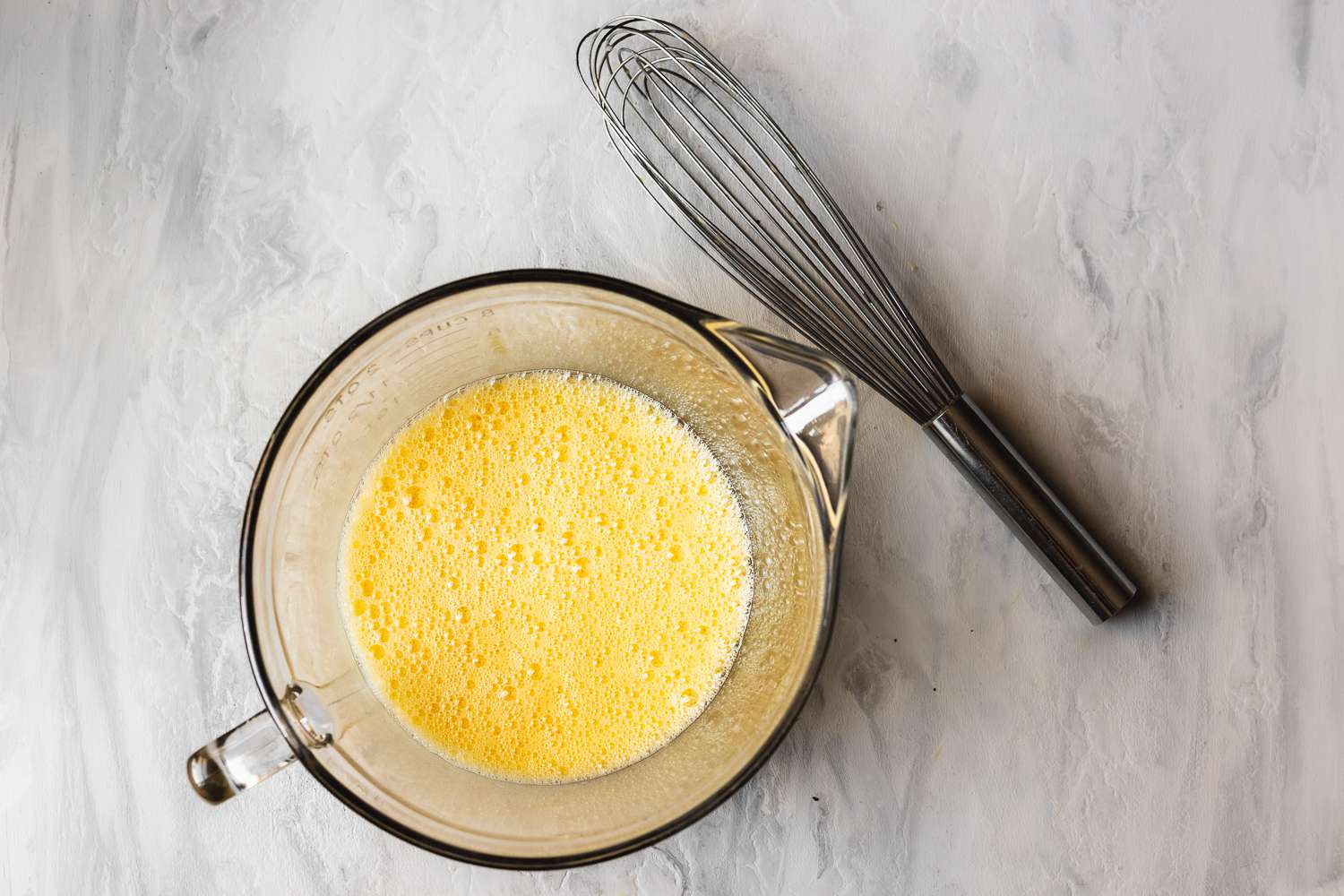 Scrambled eggs whisked together in a measuring cup with a whisk