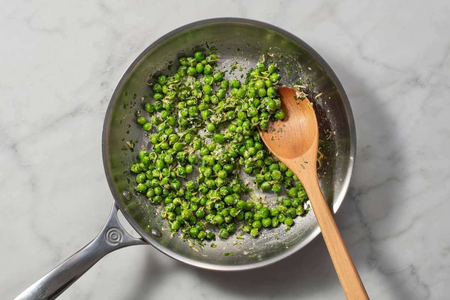Parsley, salt, pepper, and lemon zest added to the pan of cooked peas