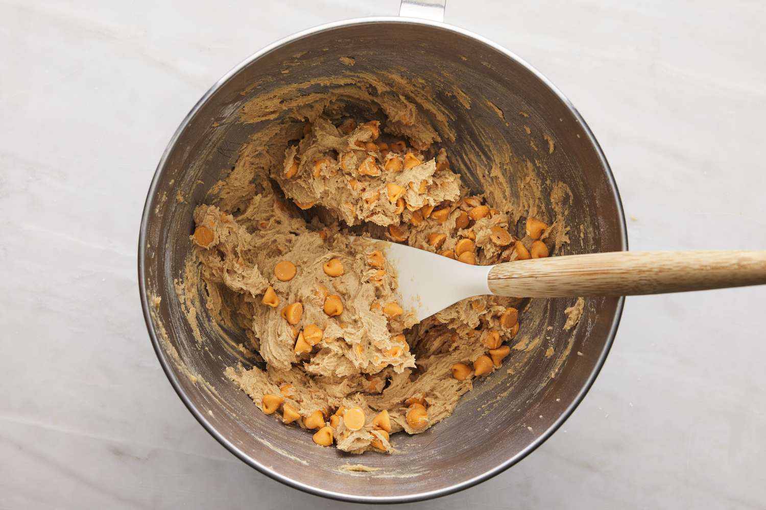 butterscotch chips folded into cookie batter using spatula