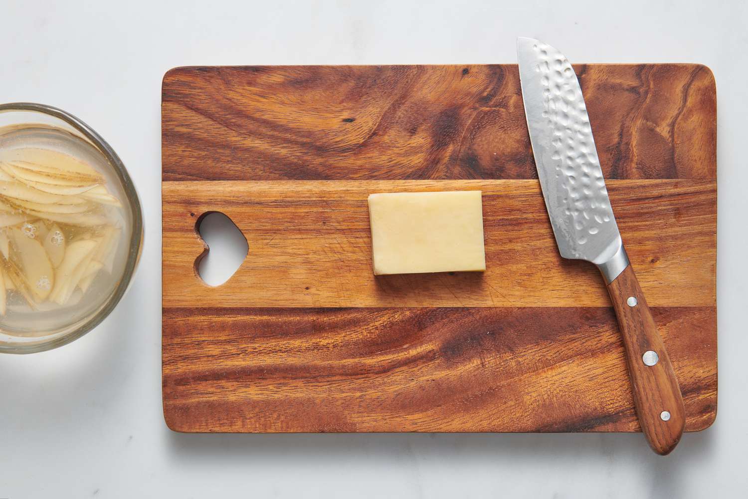 A cutting board with a stack of thinly sliced potatoes cut into a rectangle