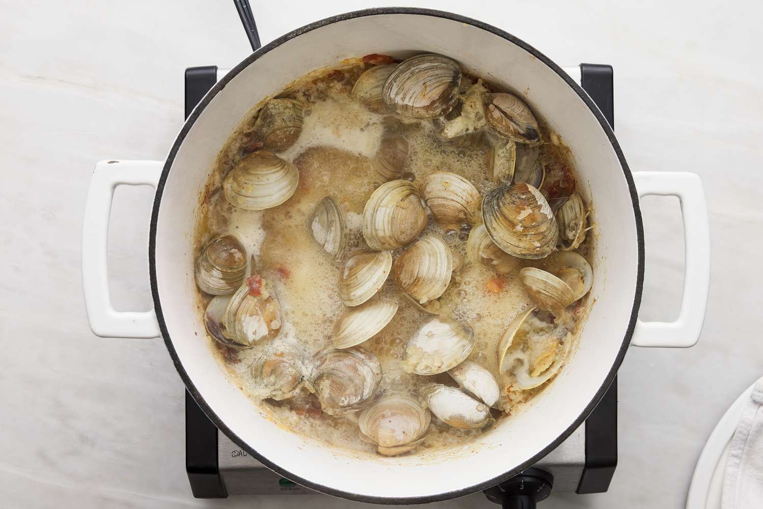 wine and clams added to dutch oven pot with bacon and onions
