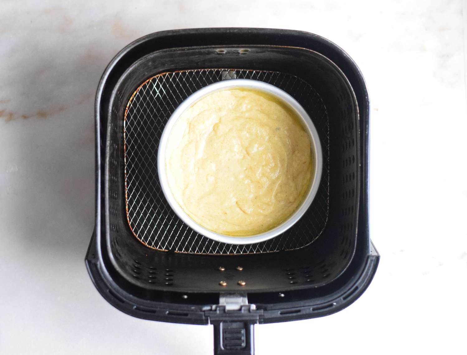cornbread batter in a pan in an air fryer basket