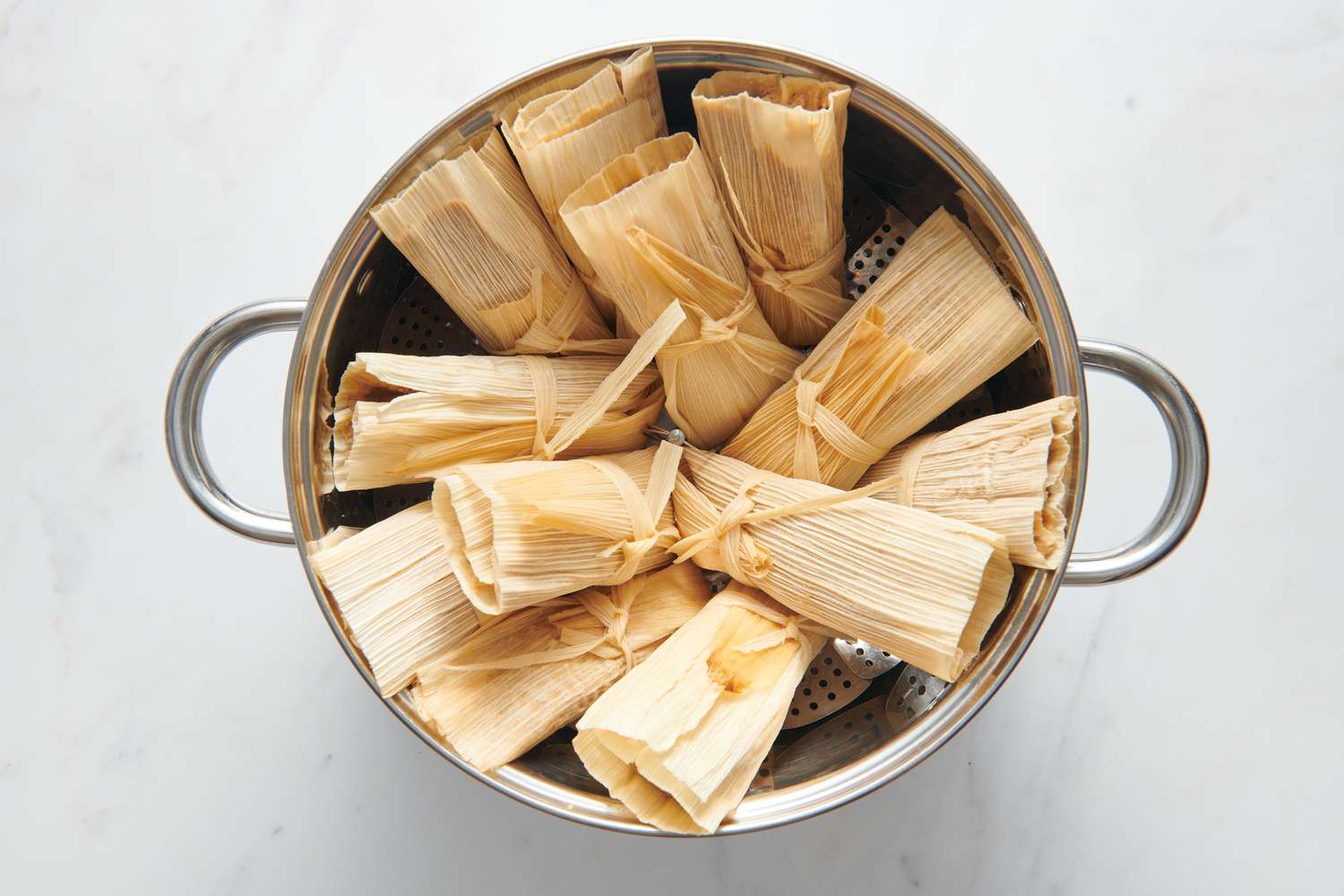 A large steamer basked with tamales standing upright