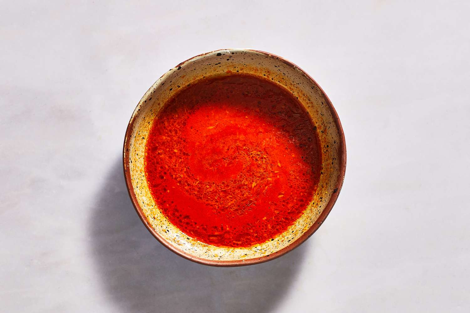 A bowl of gochujang dressing, made from gochujang, orange zest, orange juice, lime juice, and olive oil