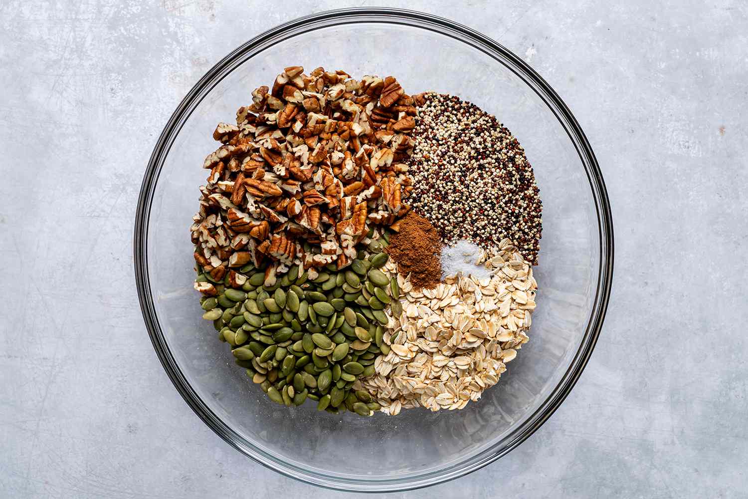 oats, pumpkin sees, pecans, quinoa, and spices in a bowl