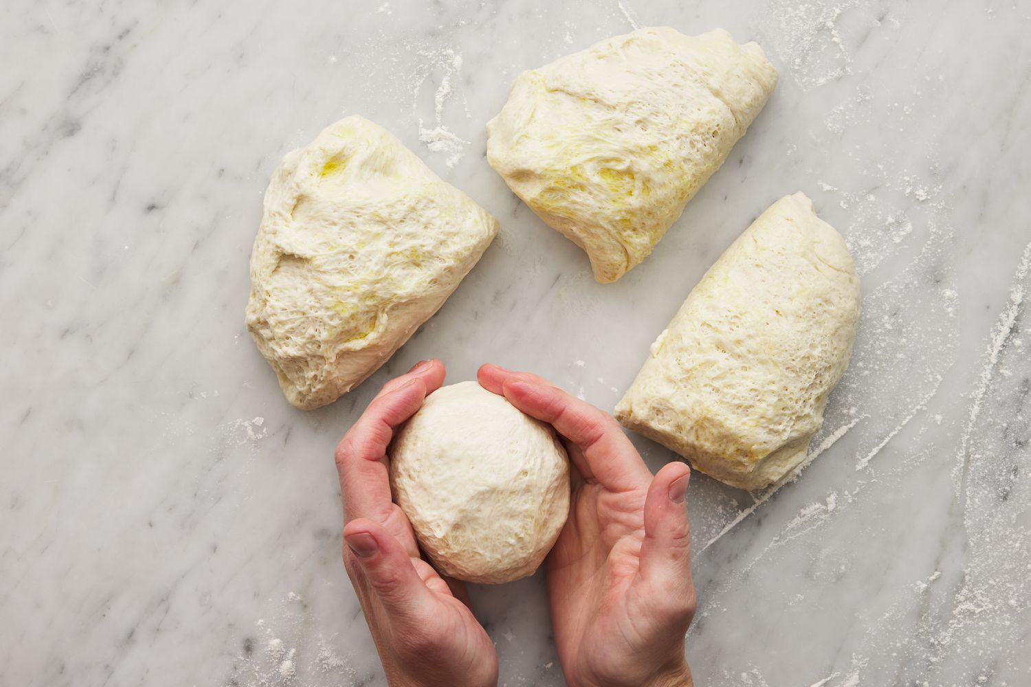 hands rolling a portion of calzone dough into a ball