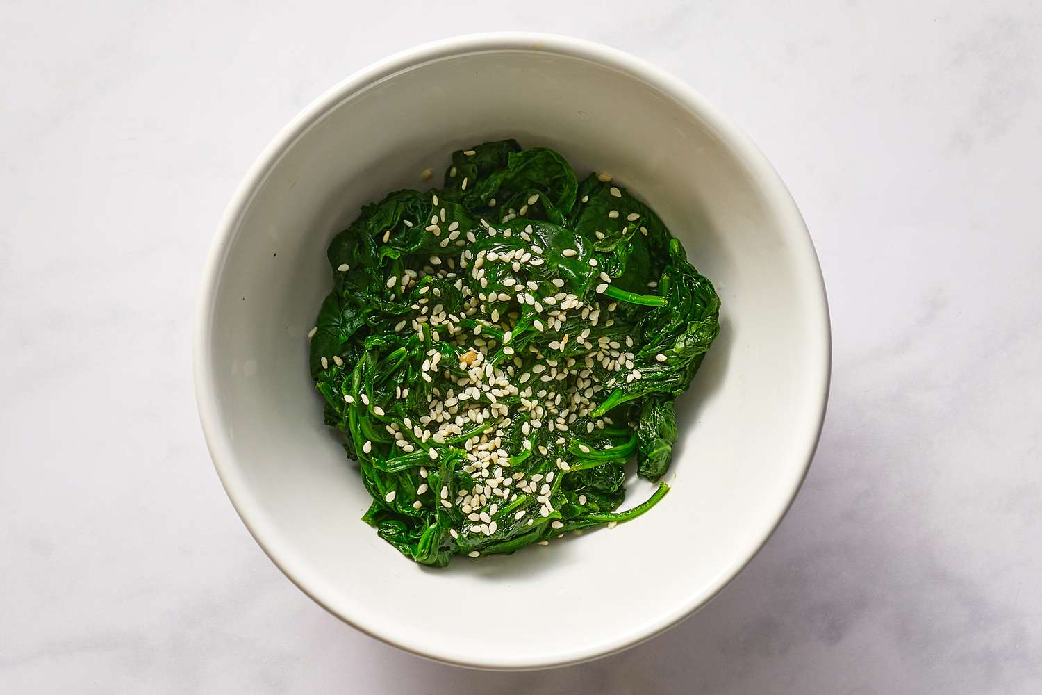 Season spinach with sesame oil, salt, and sesame seeds