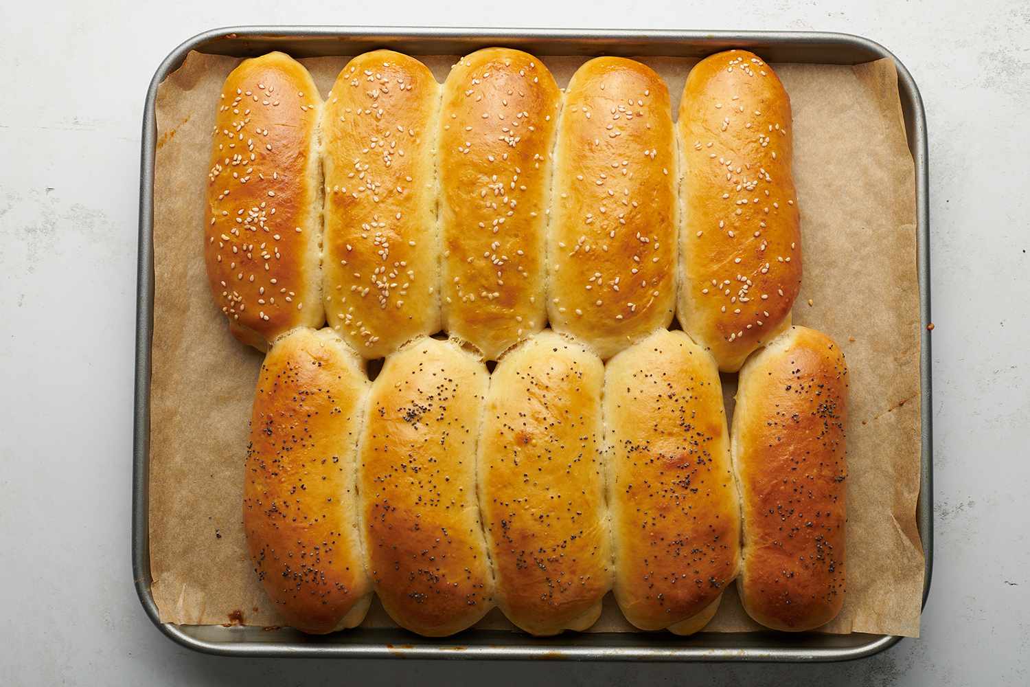 Baked hot dog buns on a parchment paper lined baking sheet 