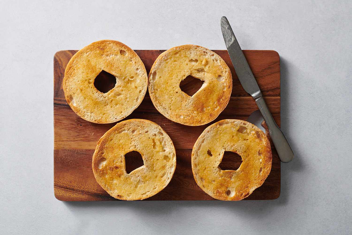 toasted bagel slices on a wood cutting board