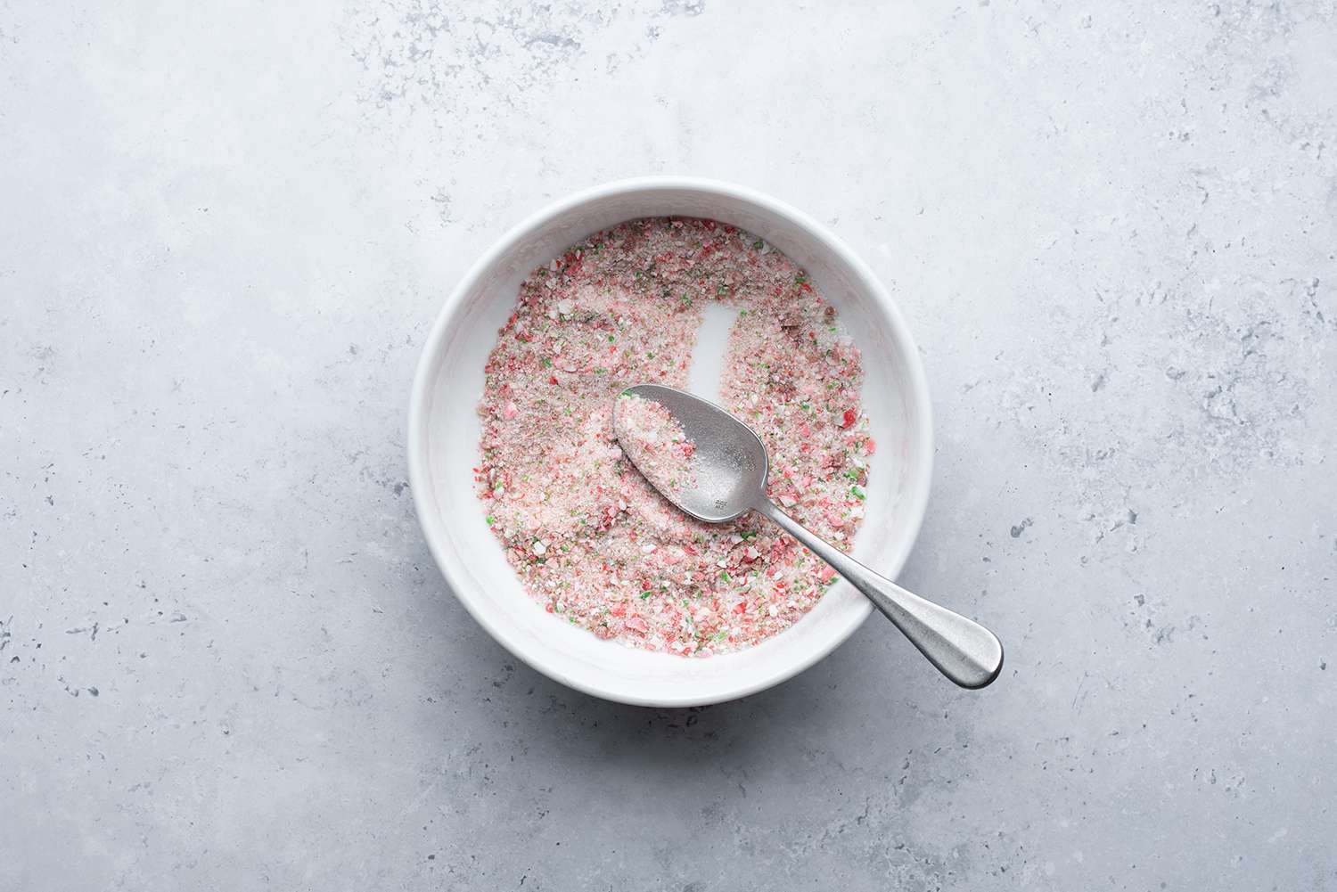 Ground candy cane with sugar in a bowl with a metal spoon 