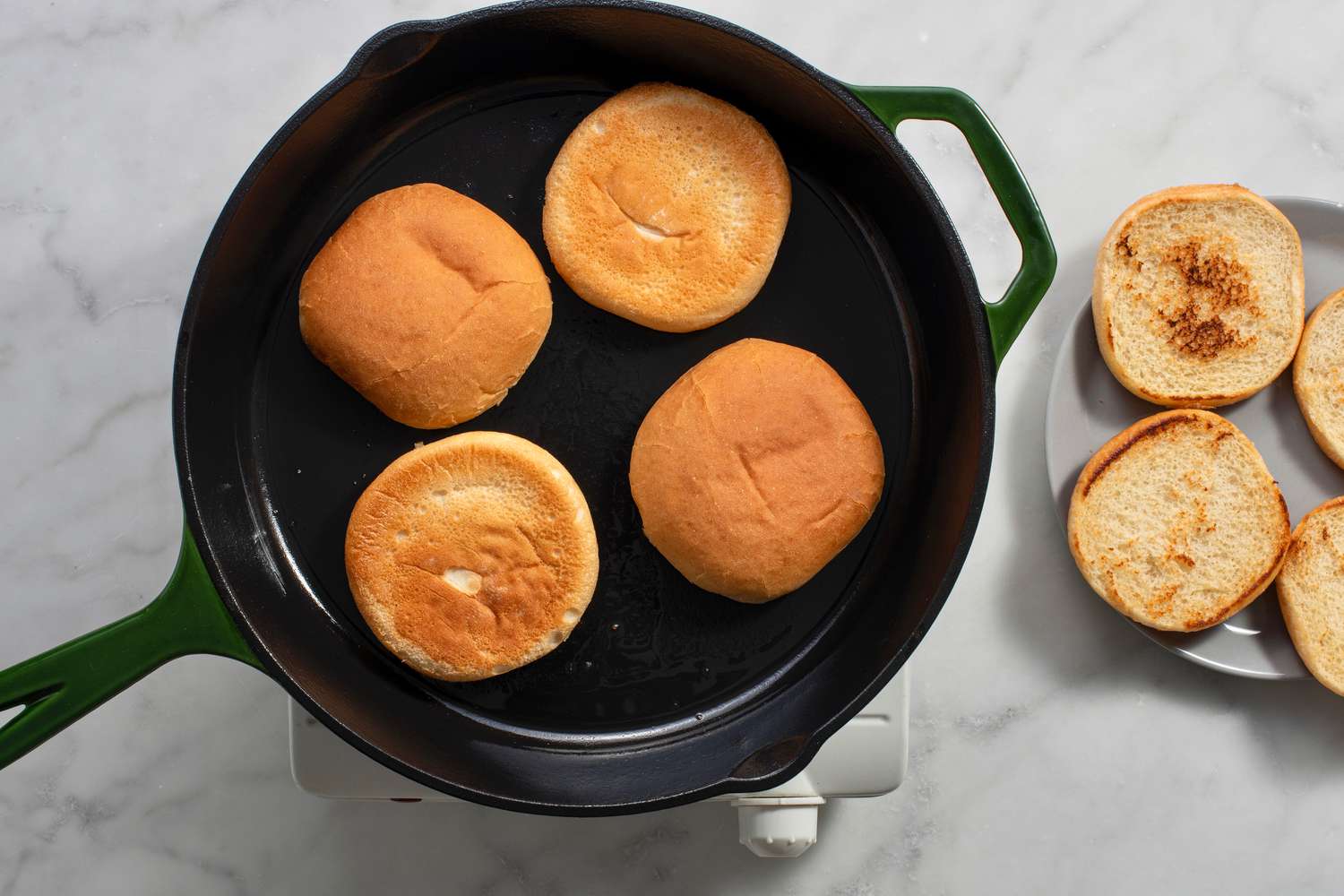 Burger buns toasting in a cast iron skillet