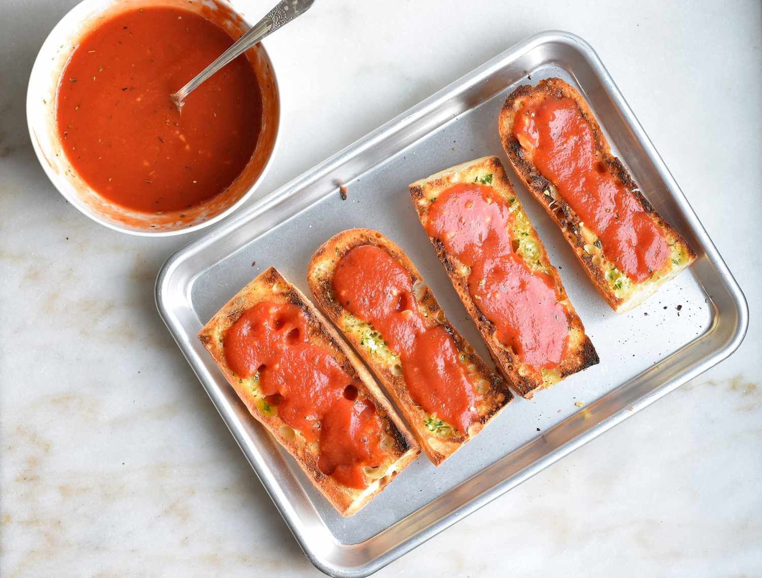 french bread covered in pizza sauce on a tray