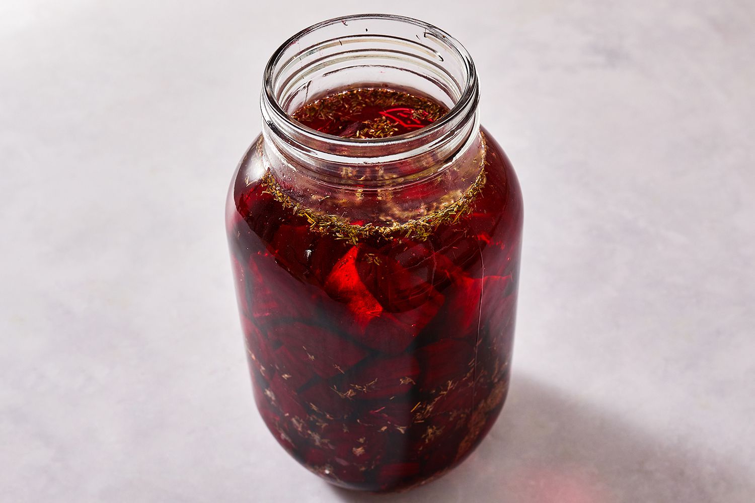 Beets, thyme, garlic, and peppercorns in a jar with the salt water 