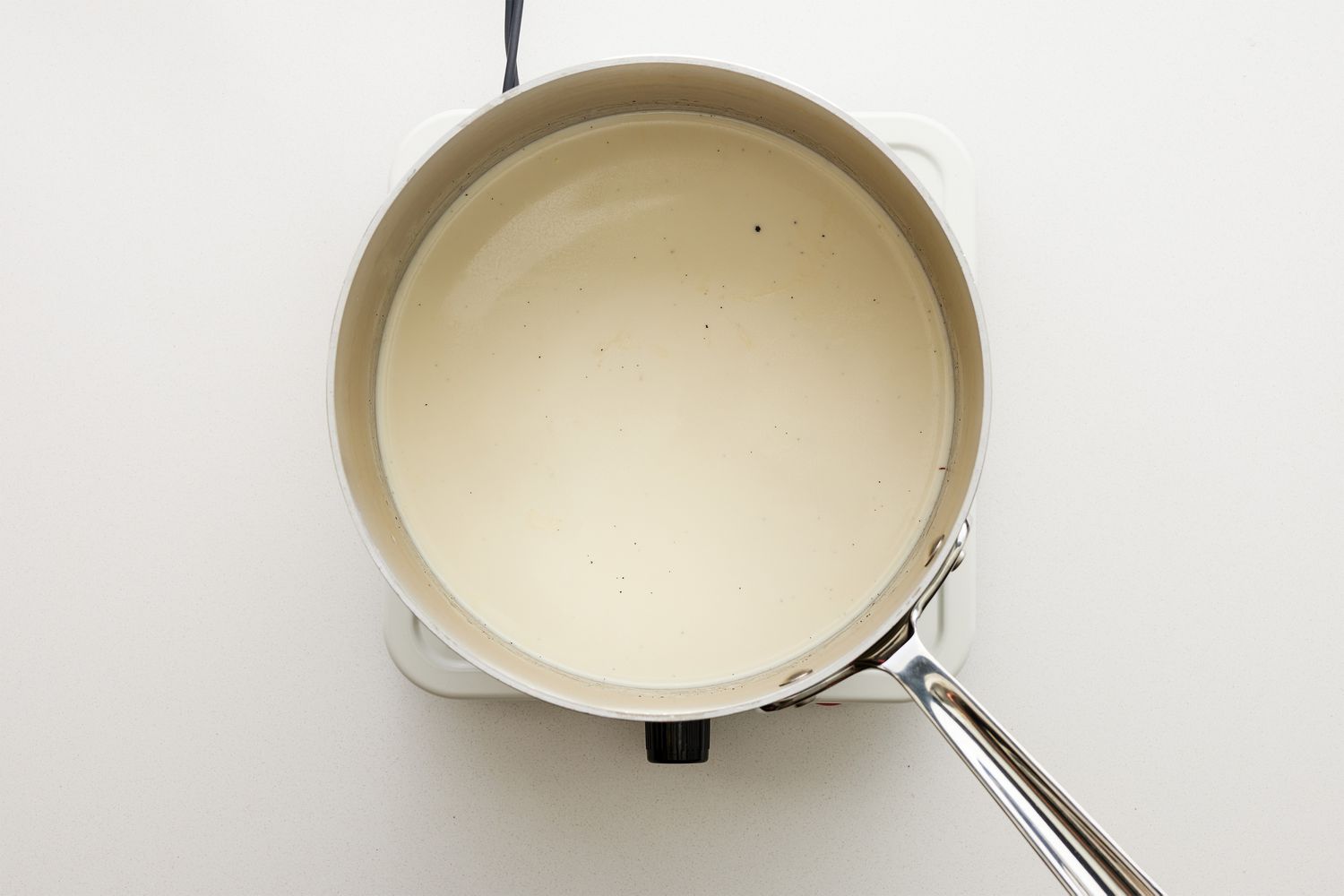A pot of heavy cream, milk, and a split vanilla bean pod