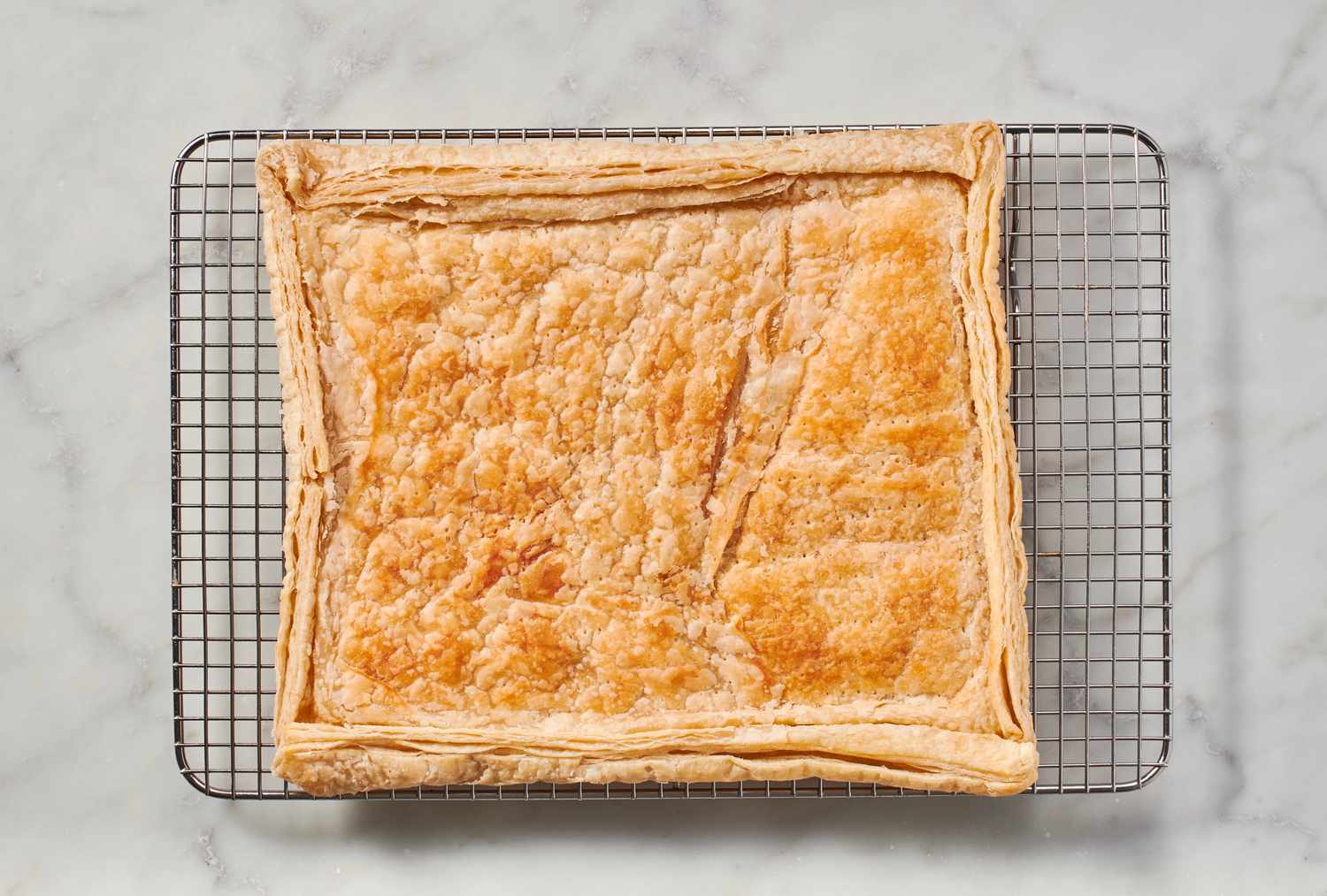 A partially baked puff pastry crust on a cooling rack