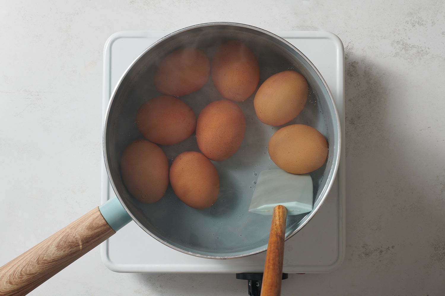 A spatula turning eggs in a pot of boiling water