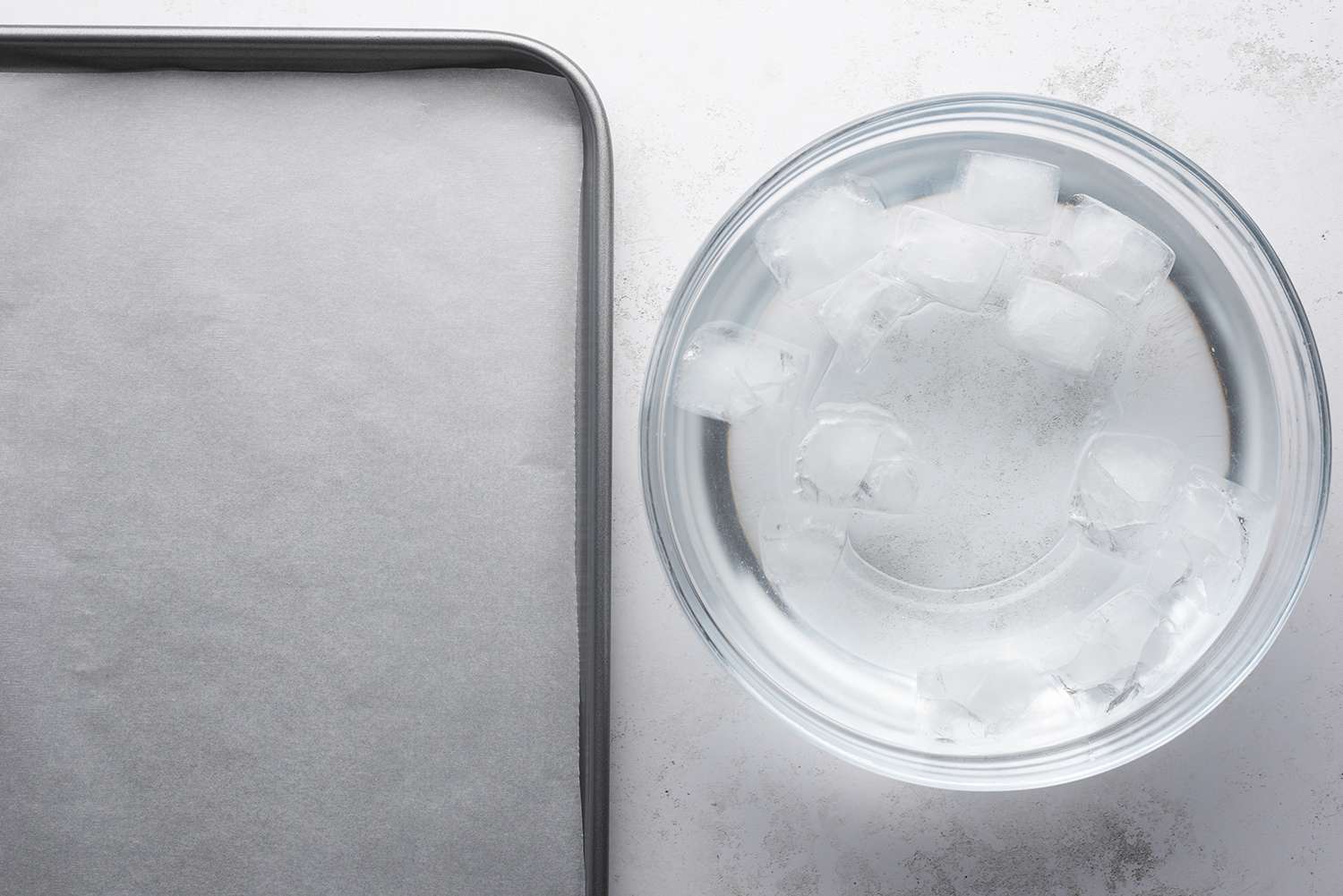 Parchment paper lined baking sheet and ice water in a bowl 