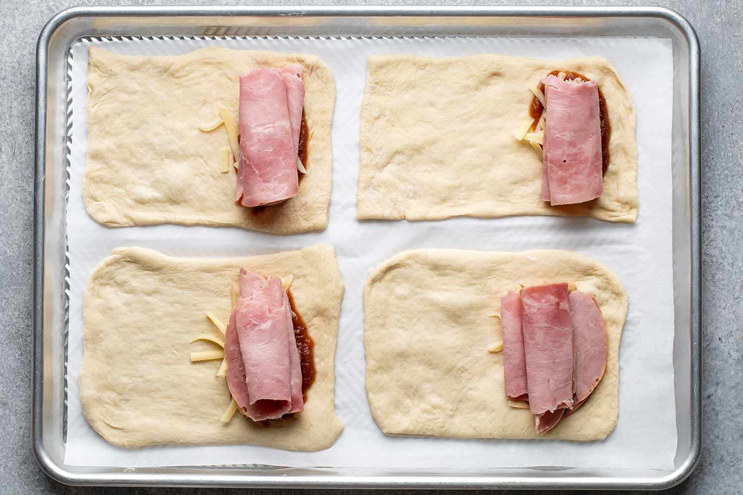 rolled up deli meat on unbaked rectangular pieces of bread dough