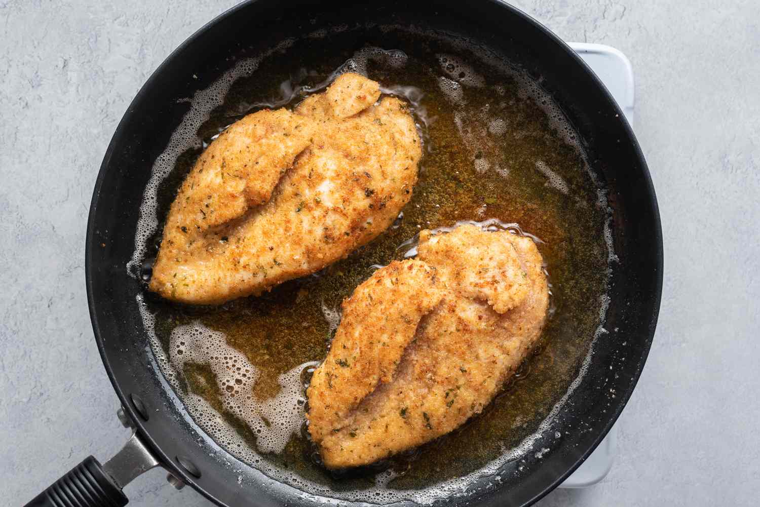 Chicken browning in a skillet with hot oil