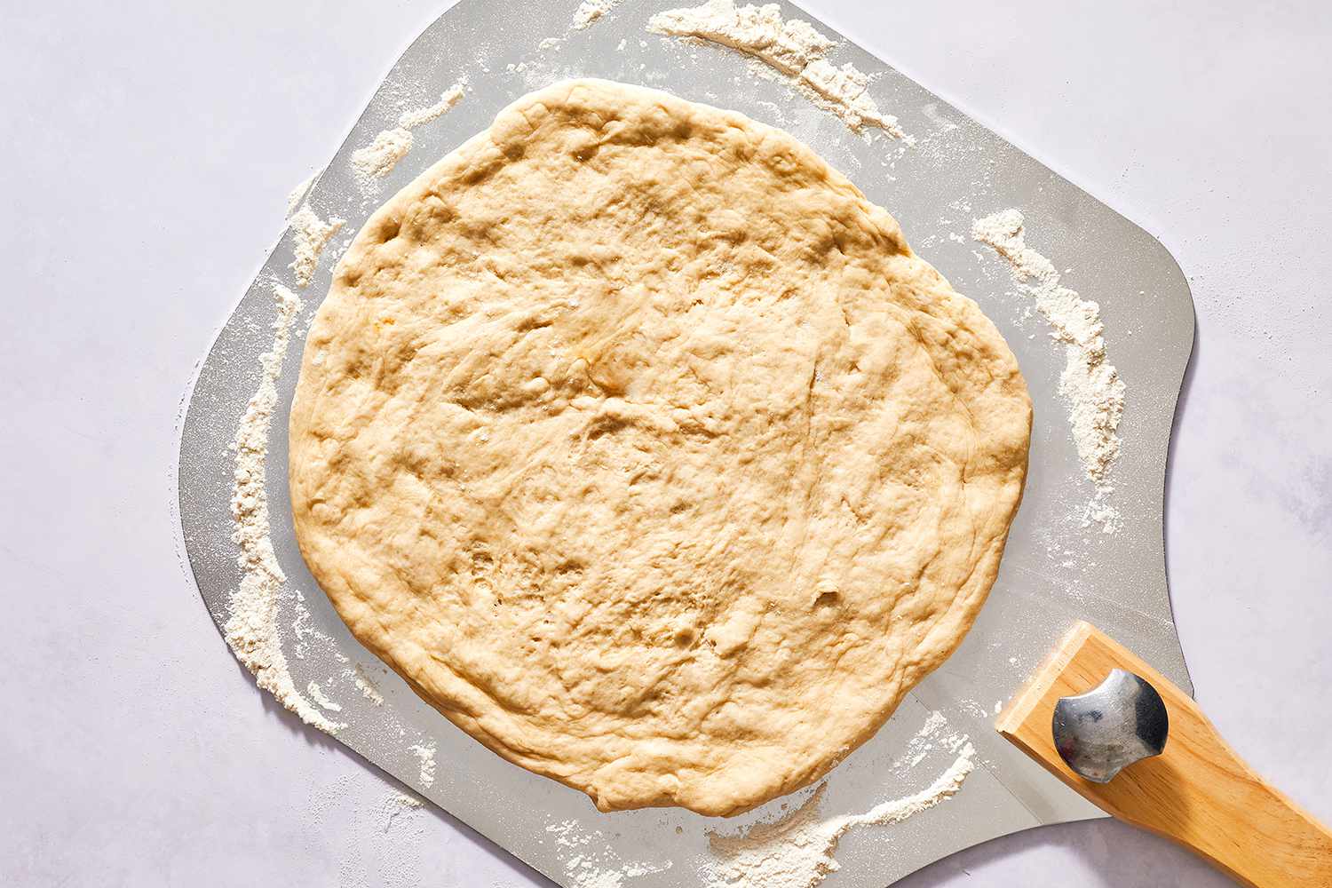 Pizza dough stretched out on a pizza peel