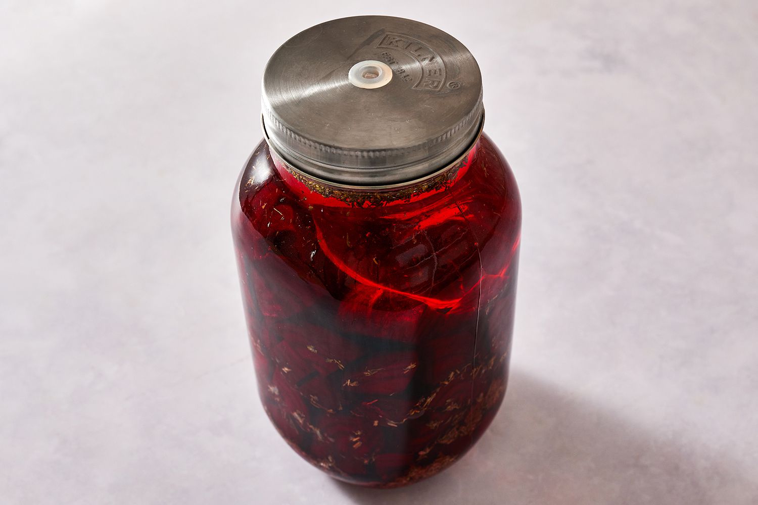 Beets, thyme, garlic, and peppercorns fermenting in a jar with a lid 