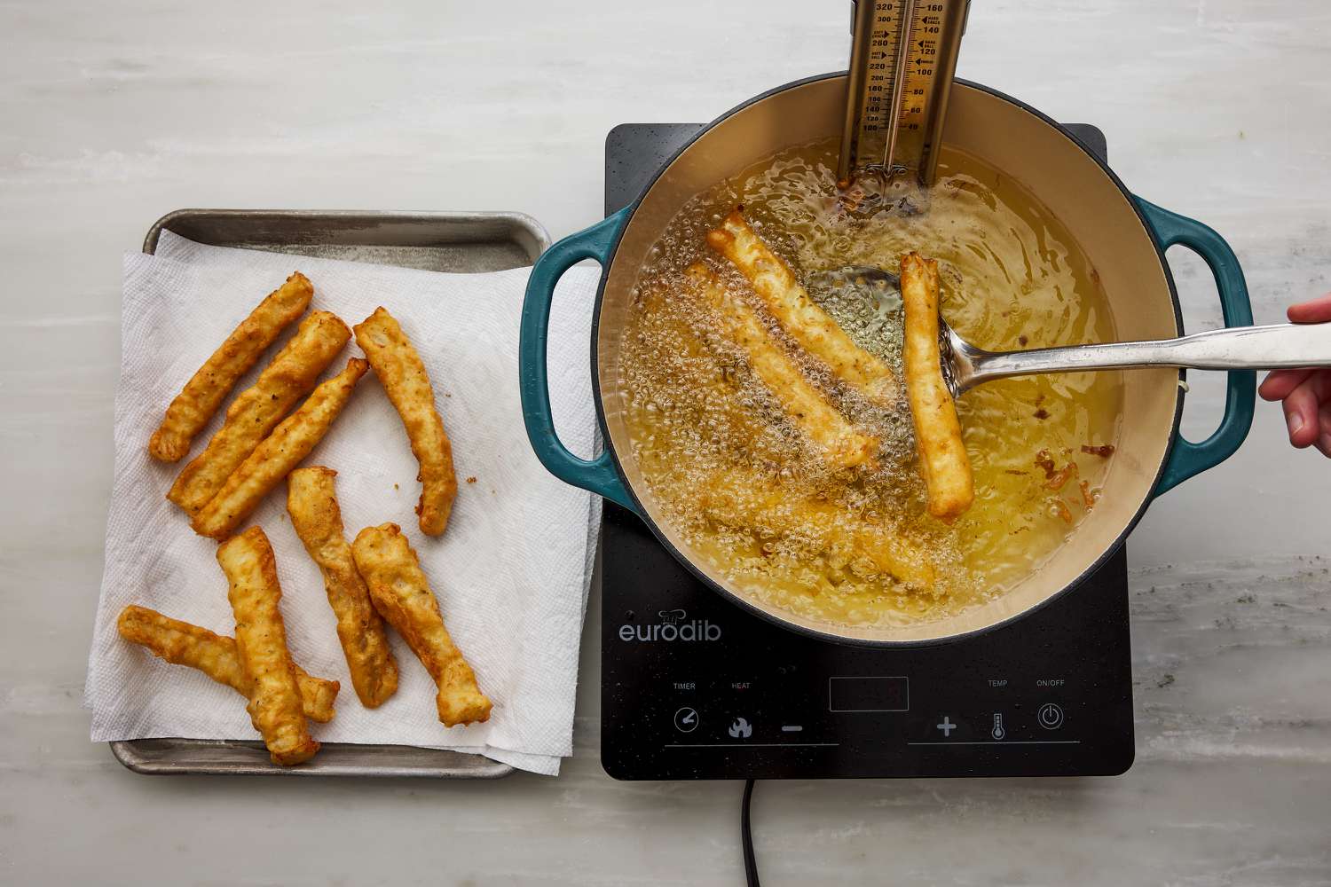 removing cod from frying oil and draining pieces of cod on paper towel