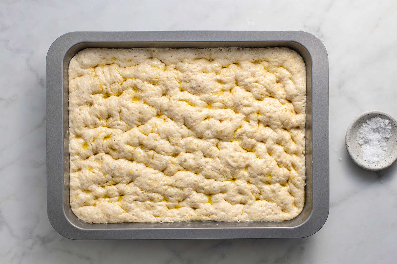 Focaccia dough in a baking dish, sprinkled with salt 