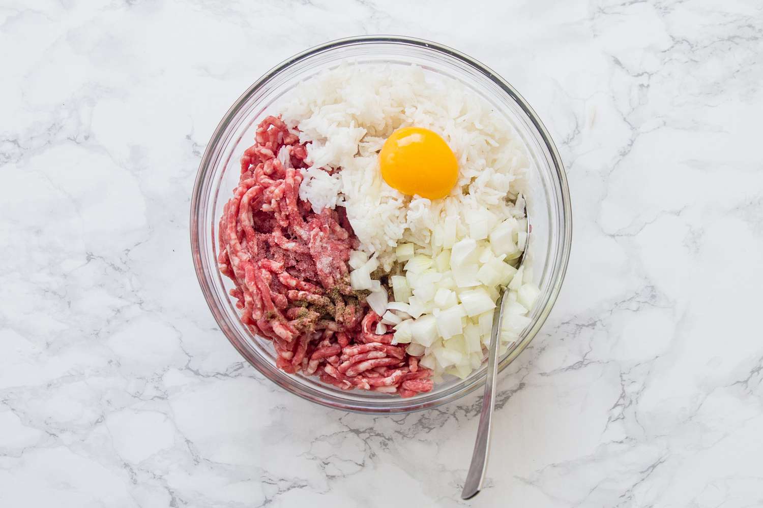Ground beef, rice, onion, egg, milk, salt, and pepper in a glass bowl