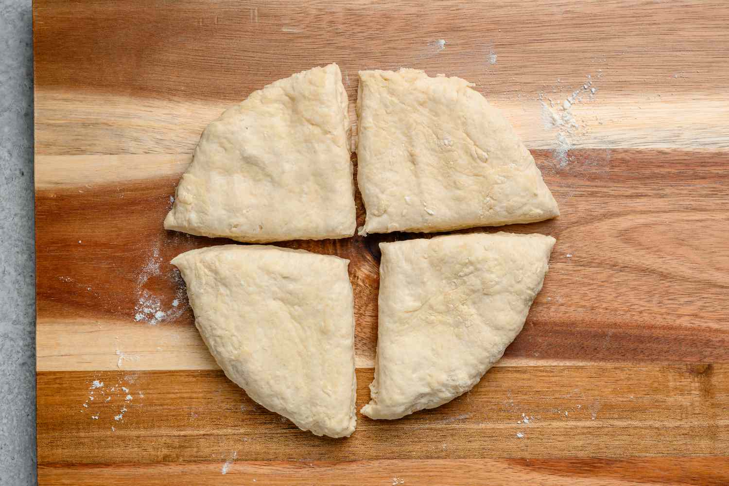 A flattened piece of round dough cut into four equal wedges