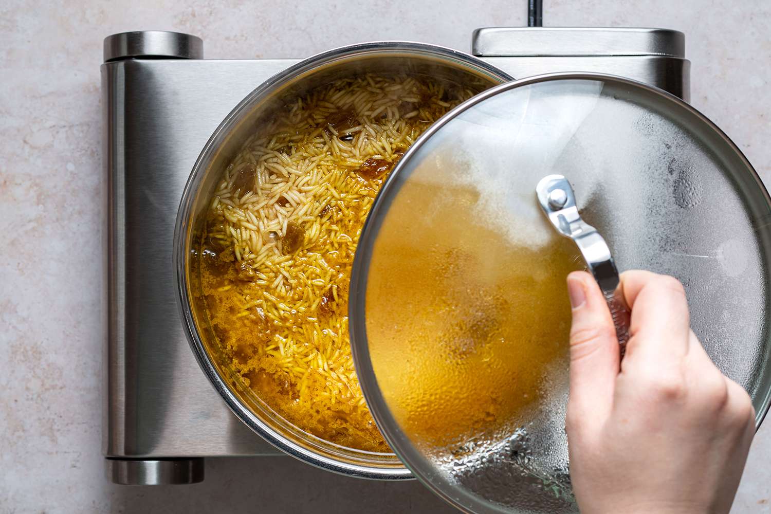 Turmeric Rice cooking in a pot on a burner, covered with a lid 