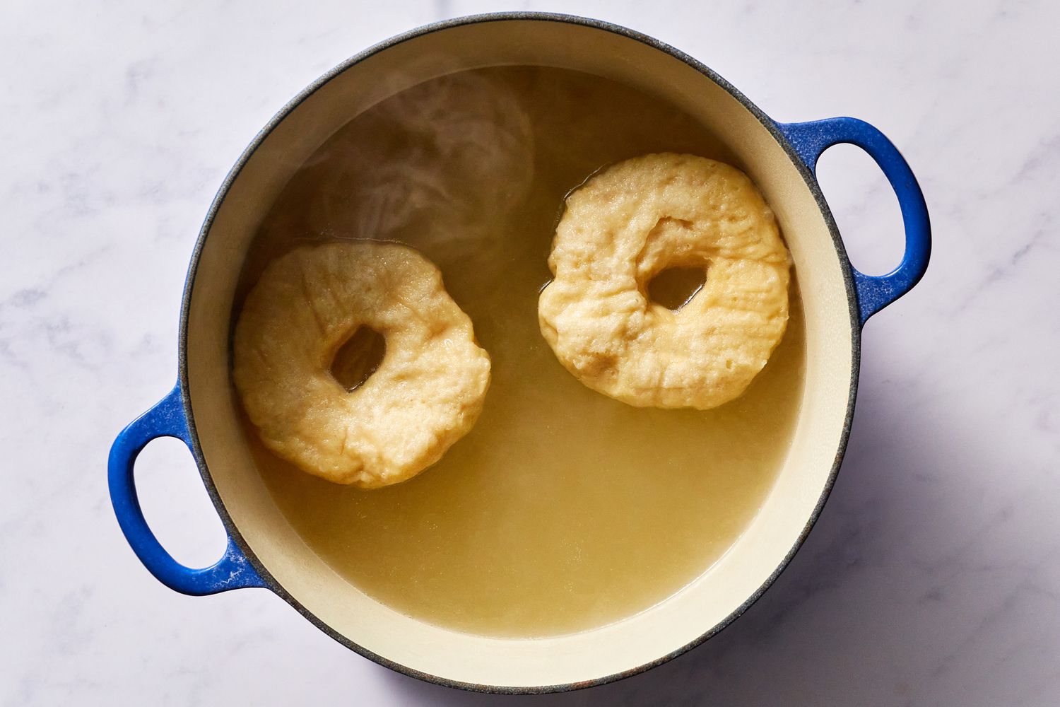 Bagels poaching in a pot of boiling water 